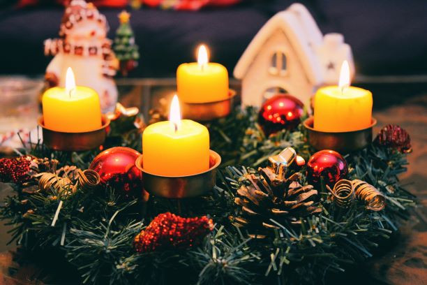 Four Yellow Lighted Candles with Christmas decorations